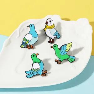 Detail view of four colorful cartoon bird enamel pins displayed in a white ceramic tray