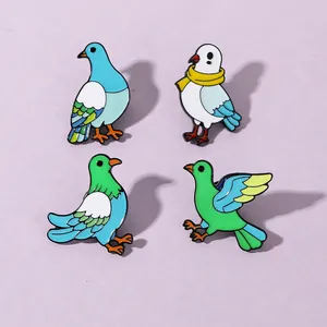 Detail view of four colorful enamel pigeon brooches in light blue and green metal
