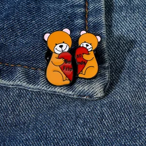Detail van twee cartoon beer emaille spelden met 'Best Friends' tekst op denim