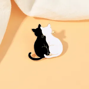 Detail of enamel cat brooch showing two black and white cats leaning together on a sweater