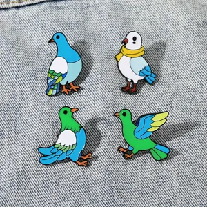 Detailed view of four colorful enamel bird brooches pinned on blue denim fabric