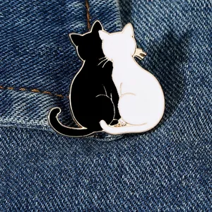 Close-up of black and white enamel cat pins on a denim fabric background texture