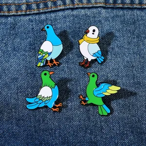 Detail of four colorful enamel pigeon brooches on blue denim fabric background