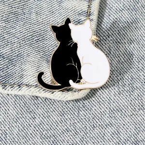 Zinc alloy black and white cat enamel pin accessory pinned on blue denim fabric texture
