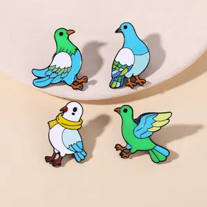 Detailed macro view of four green and blue bird enamel pins on a textured round tray