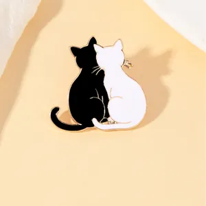 Close-up of black and white enamel cat brooch pins with elegant gold metallic finish