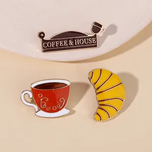 Detailansicht der Emaille-Anstecknadeln mit Kaffeetasse und Croissant-Motiv aus Metall
