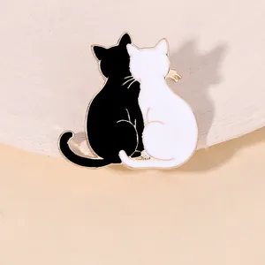 Detail of interlocking black and white enamel cat brooches with gold-plated edges and pins