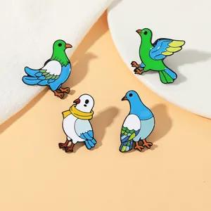 Detailed view of four colorful enamel bird brooches featuring doves on a neutral fabric