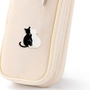 Detailed close-up of a black and white cat enamel pin pinned to a beige fabric bag