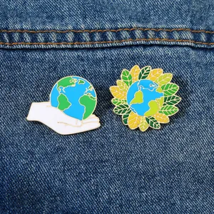 Dettaglio delle spille smaltate Earth Day su tessuto denim con design ecologici