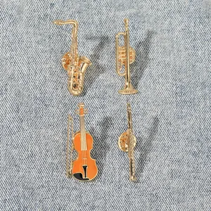 Detailed close-up of saxophone and violin enamel brooches on blue denim fabric