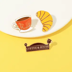 Detailansicht von Kaffee- und Croissant-Emaille-Pins mit COFFEE & HOUSE Gravurtext