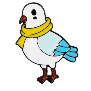 Enamel dove brooch with yellow scarf and blue wing detail in a cartoon bird pin design