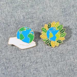 Dettaglio di spille smaltate Earth Day su denim con design a mano e girasole