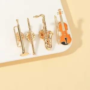 Detail view of four golden musical instrument brooches with orange accents on violin