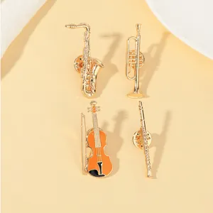 Detailed set of four golden musical instrument brooches including saxophone and violin