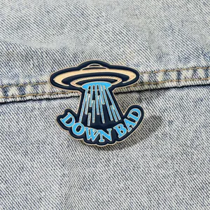 Creative blue UFO enamel pin with DOWN BAD text on denim jacket accessories