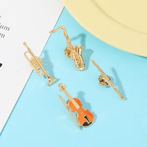 Close-up of golden music series pins featuring saxophone and violin with enamel details