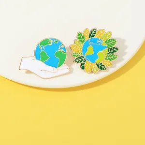 Dettaglio di spille in smalto ecologico con design della Terra e girasole su sfondo giallo