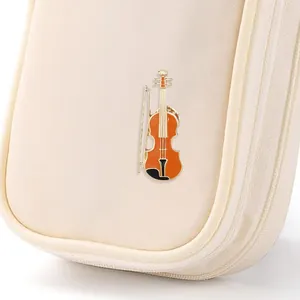 Creative violin and bow metal brooch pin with orange enamel finish on fabric background