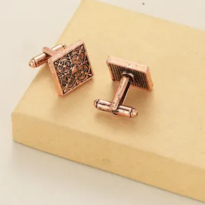Gros plan de boutons de manchette carrés en bronze avec motifs floraux vintage
