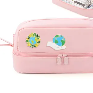Set di spille smaltate Earth Day con globo e foglie verdi su un astuccio rosa pastello
