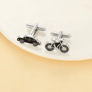 Detailed close-up of novelty cufflinks featuring vintage car and bicycle designs on a plate