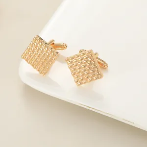 Macro shot of gold square cufflinks featuring geometric textures and bullet back closure