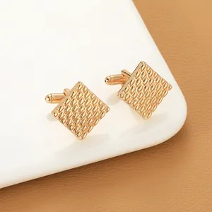 Detailed view of square gold cufflinks with textured geometric diamond pattern