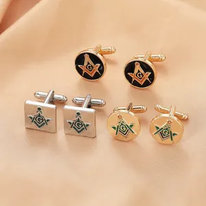 Détail de boutons de manchette maçonniques en or et argent sur un tissu de satin