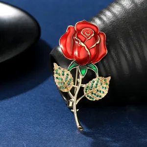 Vue détaillée d'une broche rose en émail rouge de luxe avec strass verts et tige dorée