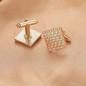 Close-up of rose gold square cufflinks with woven texture on luxury silk background