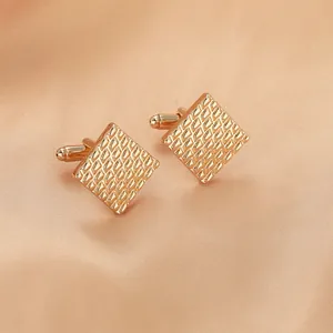 Macro detail of rose gold square cufflinks with geometric diamond texture on silk