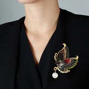 Elegant butterfly brooch with colorful crystals and pearl drop on a black blazer