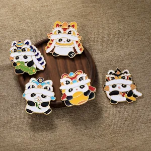 Macro di cinque spille smaltate panda danza del leone su un vassoio di legno rustico