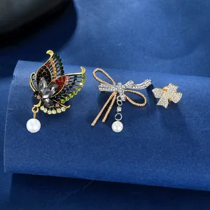 Vintage crystal butterfly and bow brooches with pearls on dark velvet background