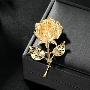 Élégante broche rose dorée avec perles et cristaux sur un coffret à bijoux noir