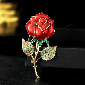 Vue macro d'une broche rose en émail rouge avec cristaux verts et métal doré
