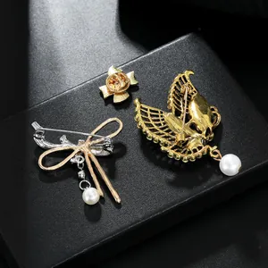 Detail view of butterfly and bird brooch backs featuring pin clasps and pearl drops