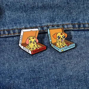 Detailed view of two cute cartoon dog pizza enamel pins on dark denim fabric background