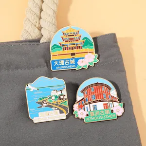 Tres pines esmaltados con monumentos de Dali fijados en un bolso de lona gris