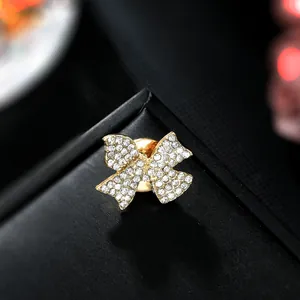 Macro detail of golden butterfly bow brooch with sparkling crystals on black texture