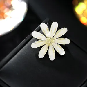 Macro di elegante spilla a margherita bianca con cuore d'oro su scatola nera