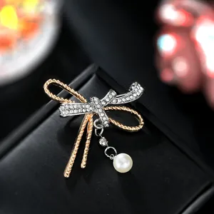 Macro detail of bicolor butterfly brooch with pave rhinestones and a white pearl drop