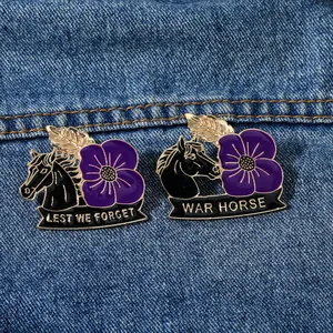Detail view of two enamel war horse poppy badges with Lest We Forget text on denim