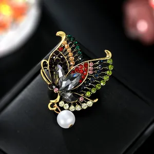 Macro shot of vintage gold butterfly brooch with colorful crystals and a white faux pearl
