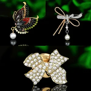 Macro view of crystal butterfly brooch and pearl bow pins on black background