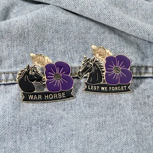 Lest We Forget War Horse purple poppy enamel badges set on light blue denim fabric
