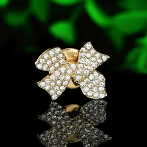 Close-up of golden butterfly brooch with white crystals on a black reflective base